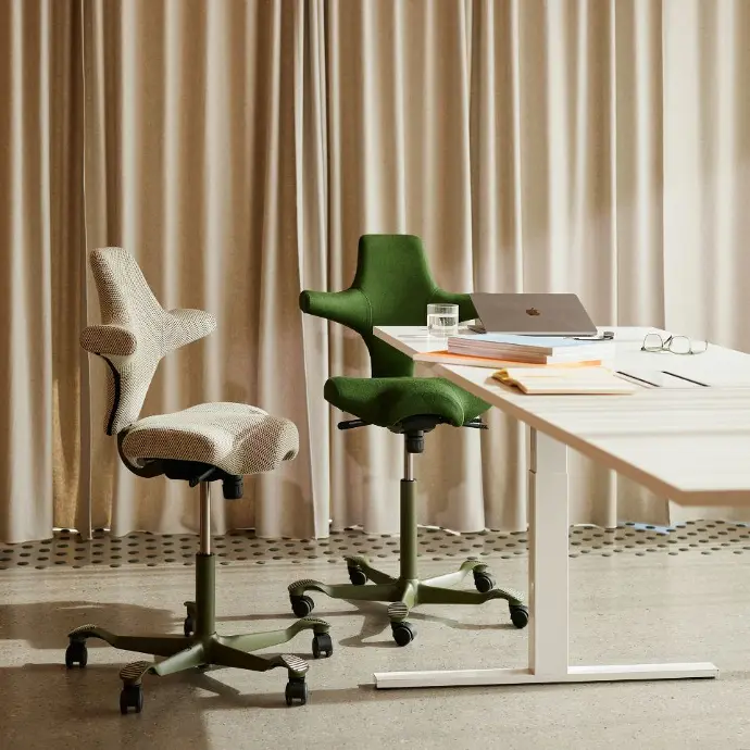 HÅG Capisco 8106 met moss frame en Kvadrat bekleding – Serpentine 0928 & Mandal 980 Twee HÅG Capisco 8106 stoelen met moss-groen frame, bekleed met Kvadrat-stof: Serpentine beige (0928) en Mandal Black Forest groen (980), in rustgevend interieur