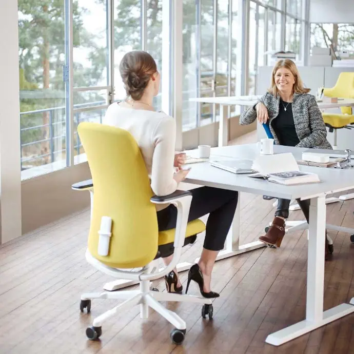 HÅG SoFi 7300 with upholstered backrest in a bright meeting or conference room Yellow HÅG SoFi 7300 office chair at a conference table